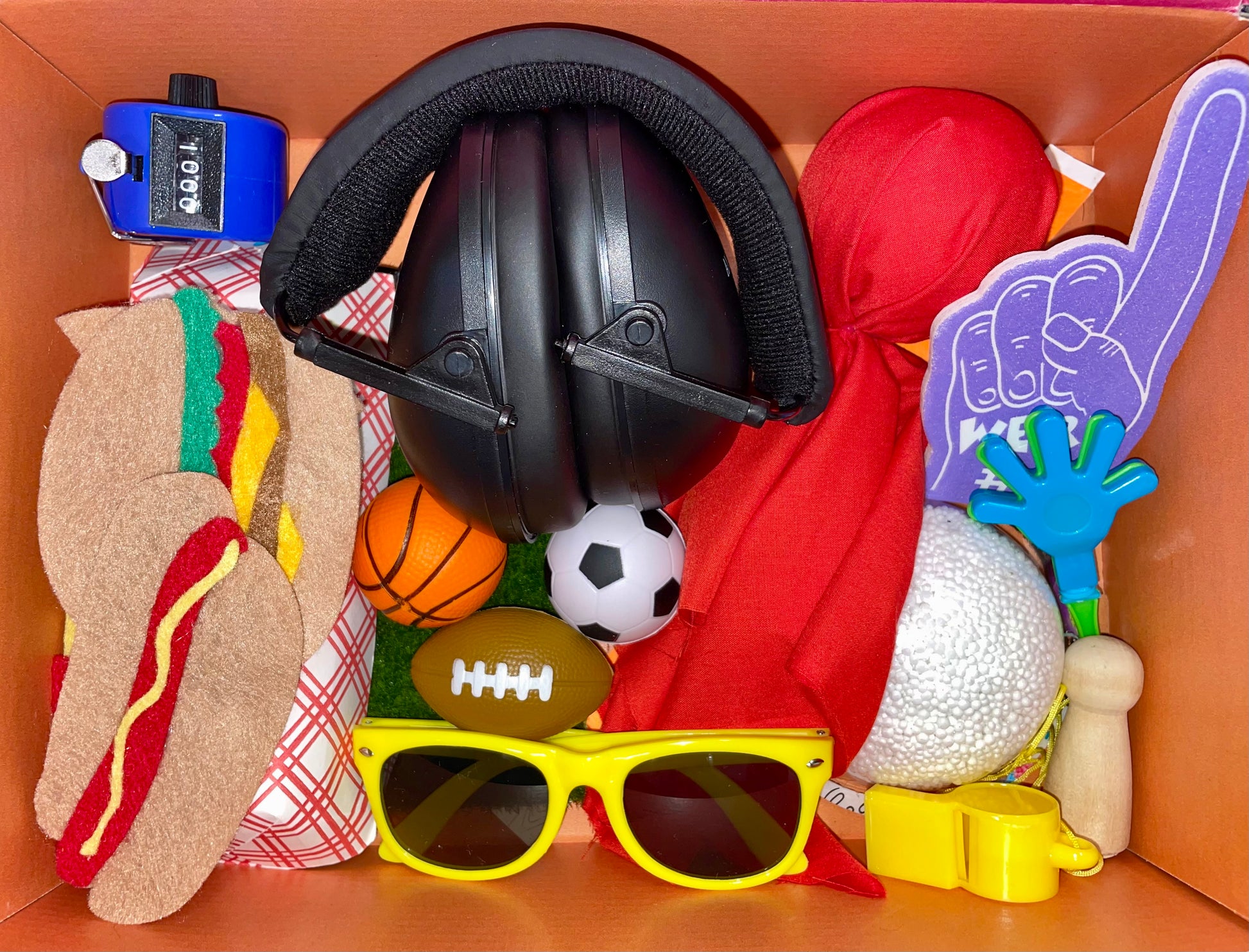 Sports themed sensory box. Headphones for kids, pitch counter, fidgets, whistle, toys, floam, pretend food.